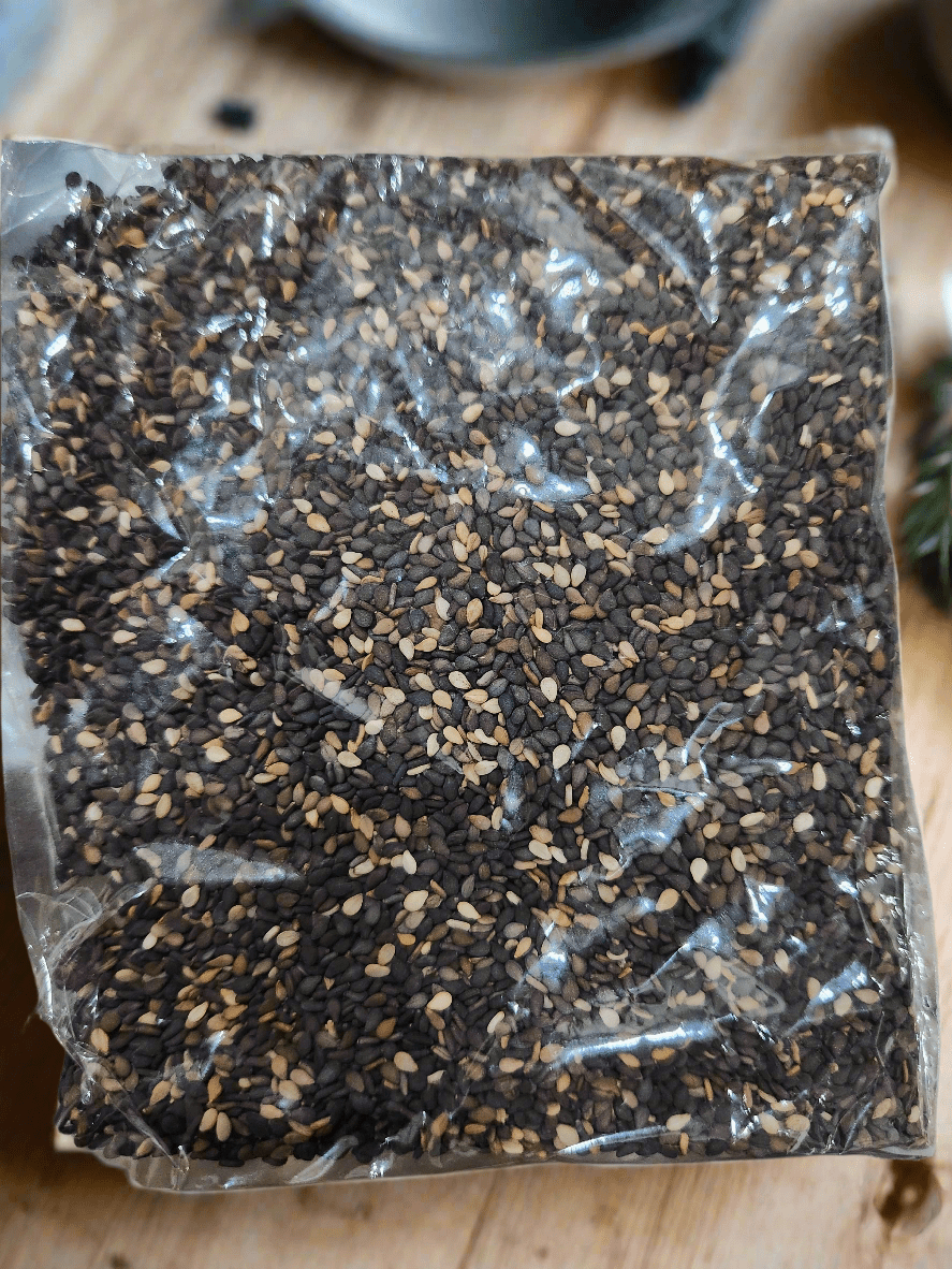 Pack of black sesame seeds in a clear bag, showcasing their rich color and texture, ideal for healthy recipes.